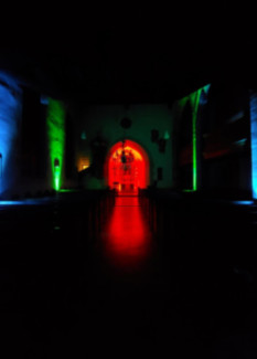 Innenaufnahme der Egidienkirche, wenn es draußen dunkel ist. Der Altar ist rot beleuchtet und an den Seiten sind weitere Scheinwerfer, die grünes und blaues Licht geben. 